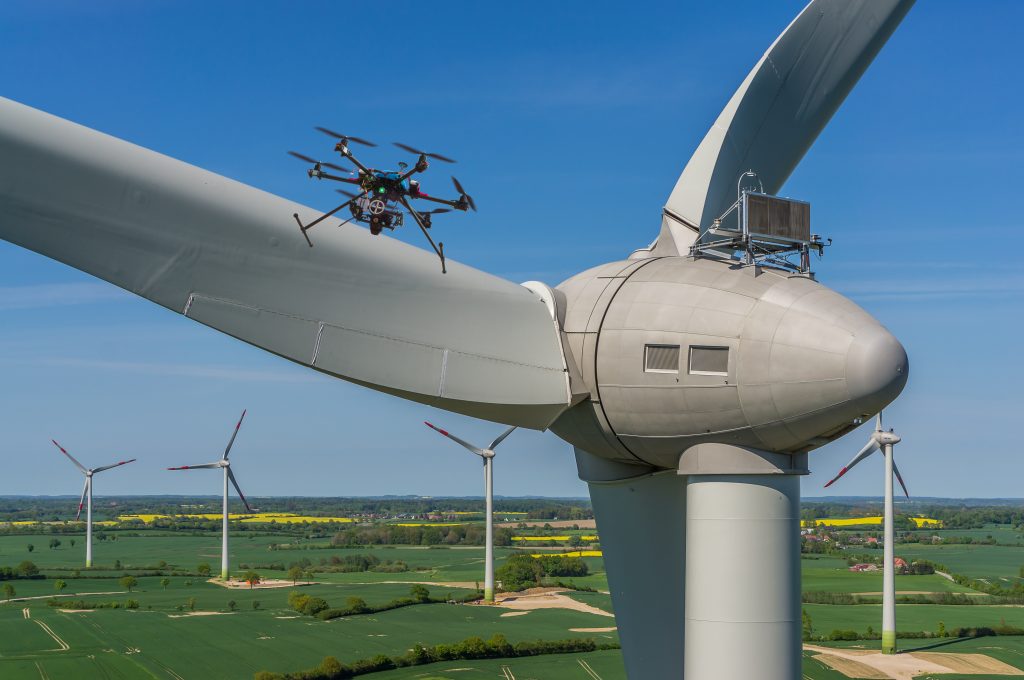 Drohne im Schwebeflug nahe an einem Windkraftwerk